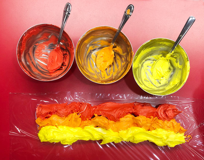 Rows of coloured icing spread on Saran Wrap